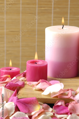 candle with colorful petals on woven background