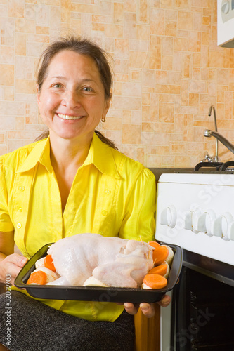 woman puting stuffed chicken  into oven photo