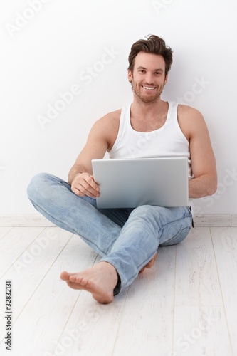 Happy man sitting on floor with laptop