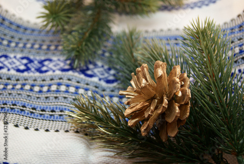 Green spruce boughs and a gilden cone in a traditional embroider photo