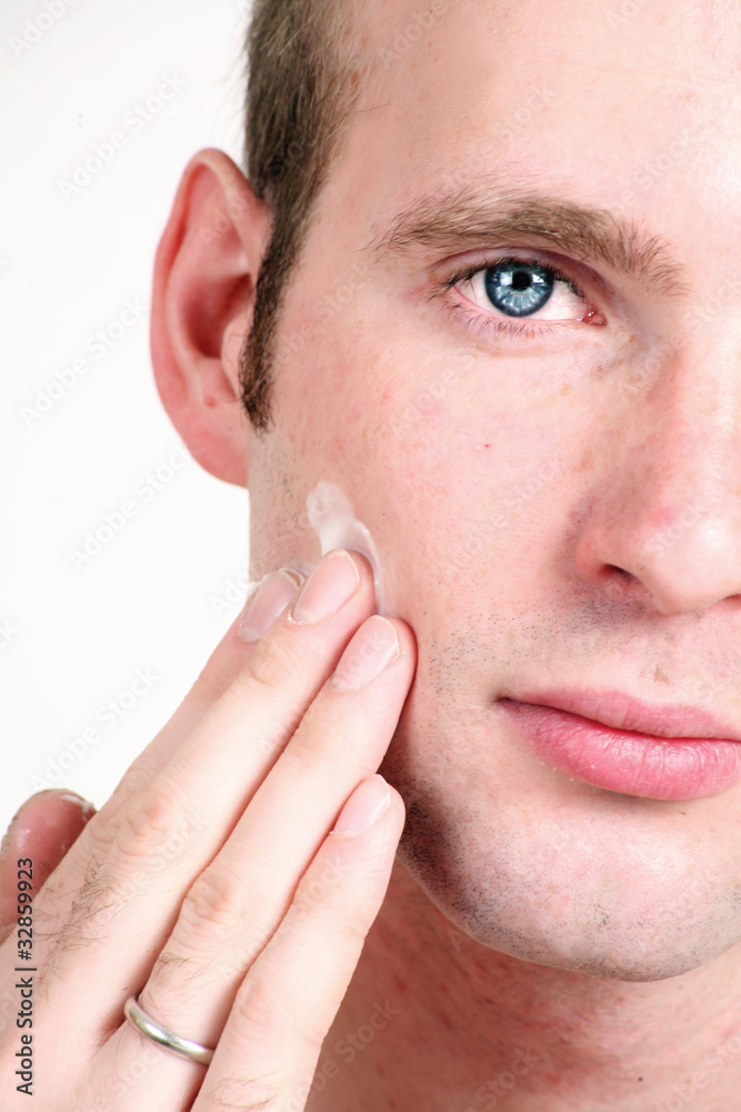 Fototapeta premium Close-up portrait of young handsome man applying face cream