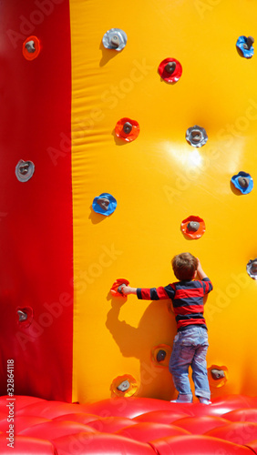Kleiner Junge beim Spielen an einer aufblasbaren Kletterwand