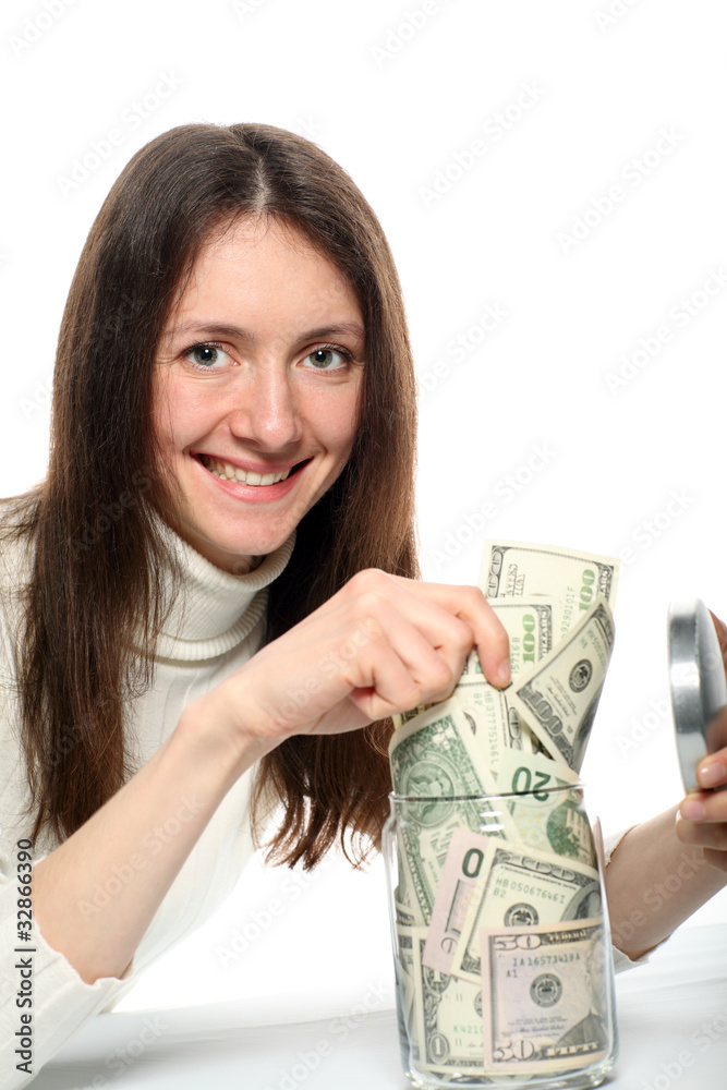 Pretty smiling young woman taking dollars from a glass jar Pretty smiling young woman taking dollars from a glass jar