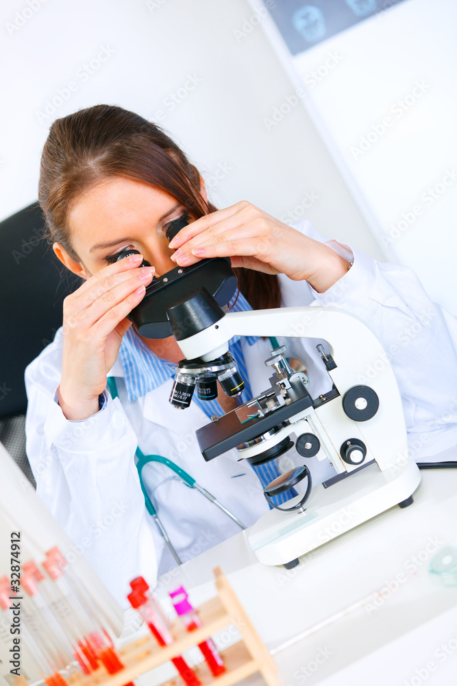 Fototapeta premium Woman researcher using microscope in laboratory. Close-up.
