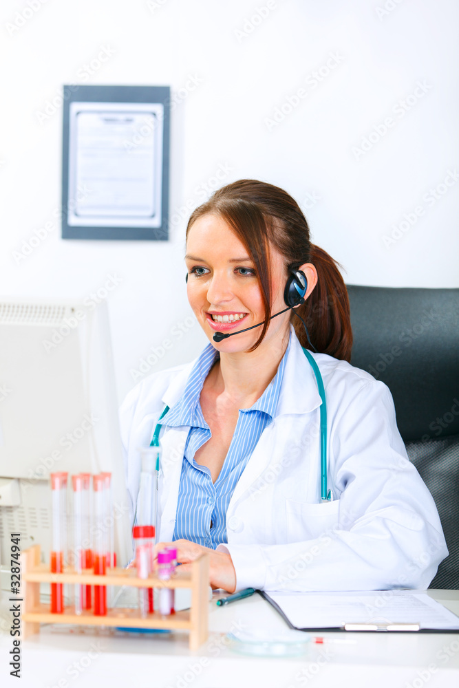 Smiling doctor woman with headset working on computer. Smiling doctor woman with headset working on computer.