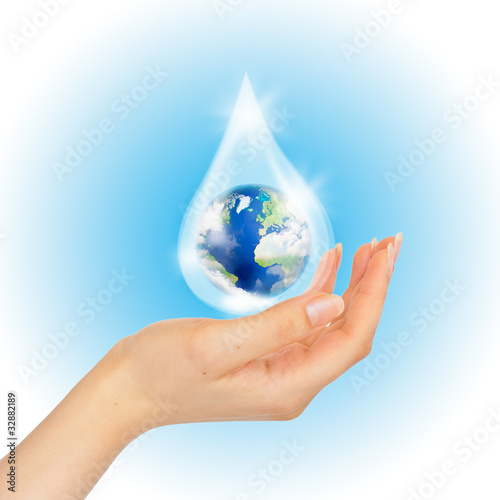 Drop of water with Earth inside and hand on white.