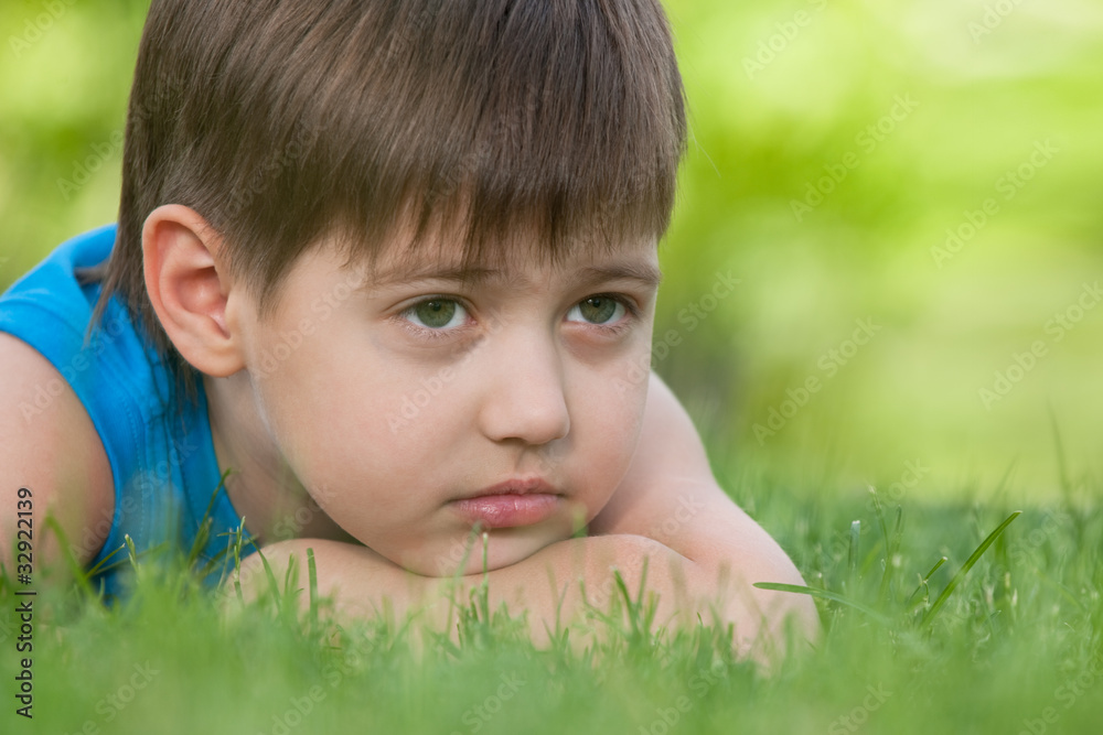 Thoughtful boy on the green grass Thoughtful boy on the green grass
