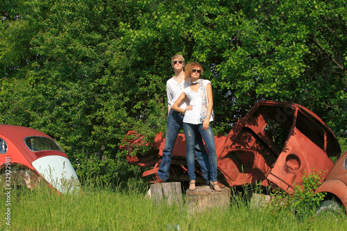 Tableau sur toile A young couple on a old car in a field