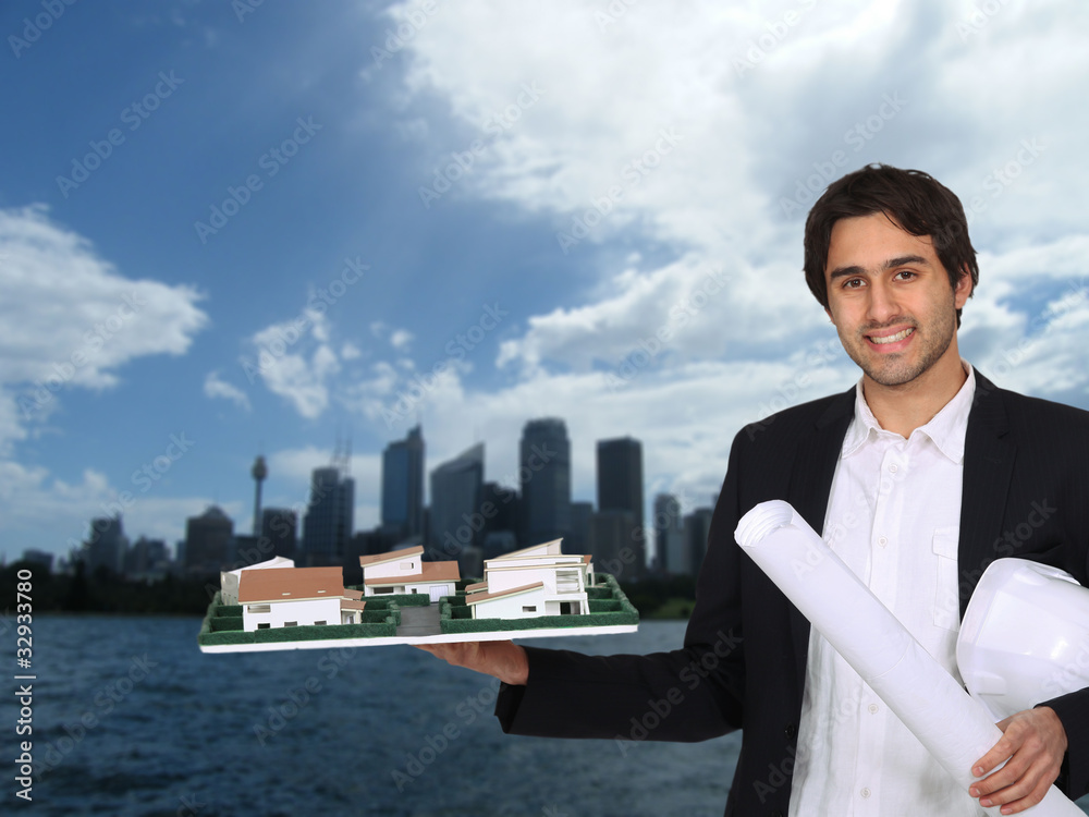 Architect holding model with urban landscape in background Architect holding model with urban landscape in background