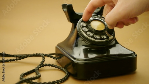 male hand on very old telephone on brown background