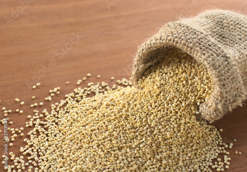 Foto Raw white quinoa grains in jute sack on wood