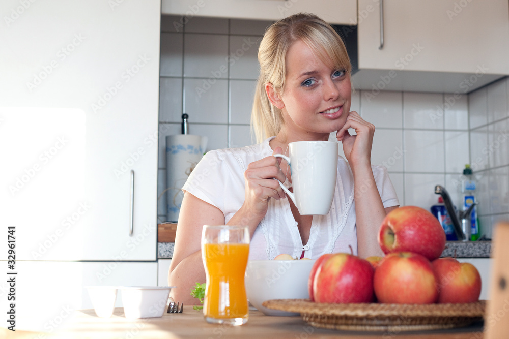 junge blonde frau mit äpfeln, fruchtsaft und tee