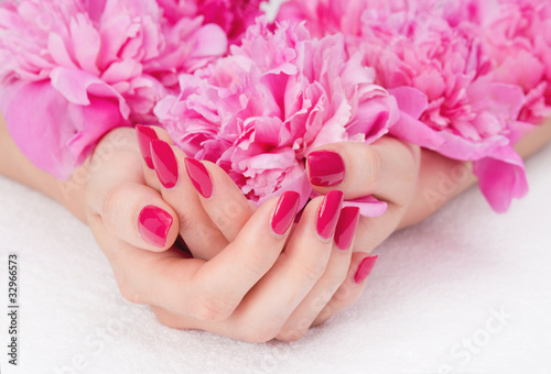 Woman cupped hands with pink manicure holding a flower