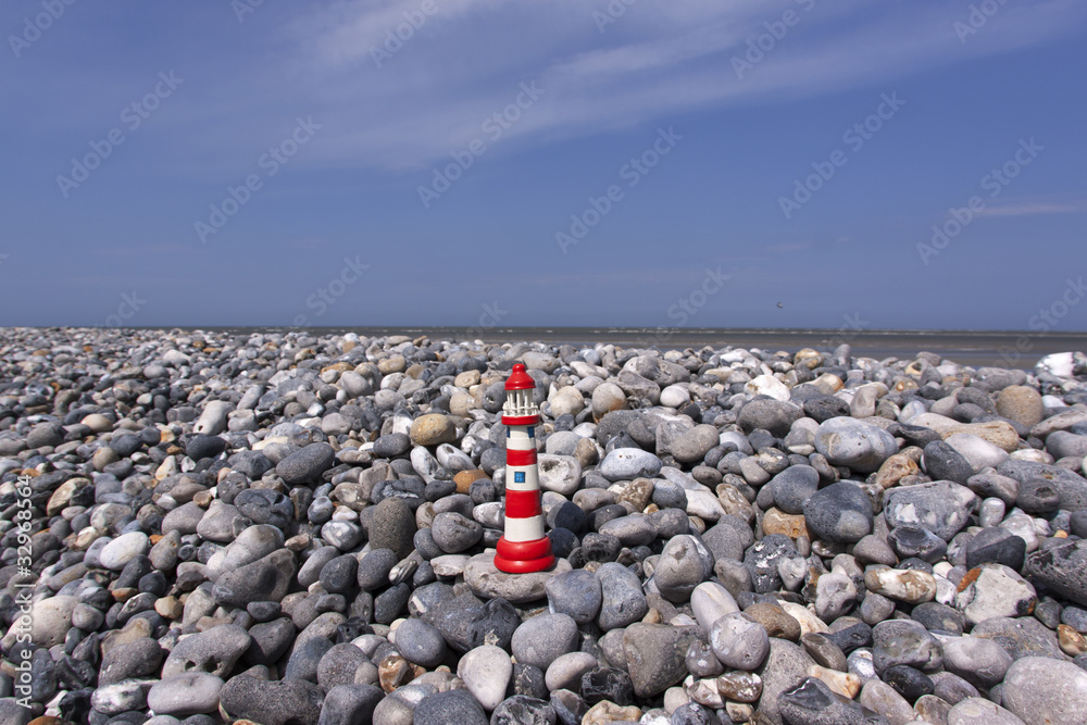 Small model lighthouse on flintstone along the coast