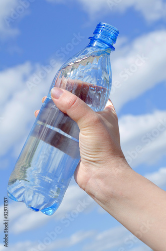 Water bottle in a hand against the sky