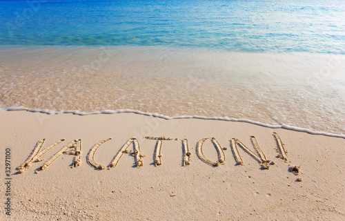 On a beach it is written "VACATION"