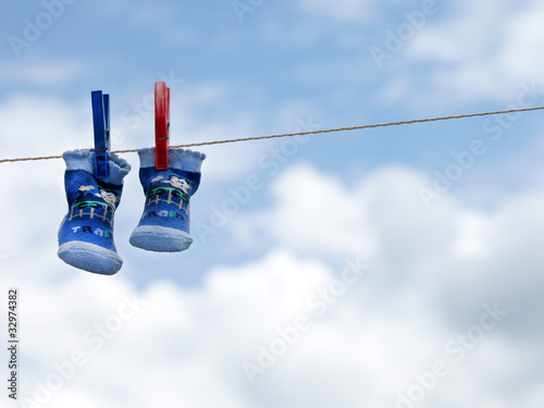Little blue socks hanging on a clothesline in front of blue sky photo