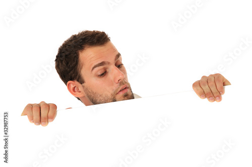 Mann schaut neugierig hinter weißer Wand hervor photo