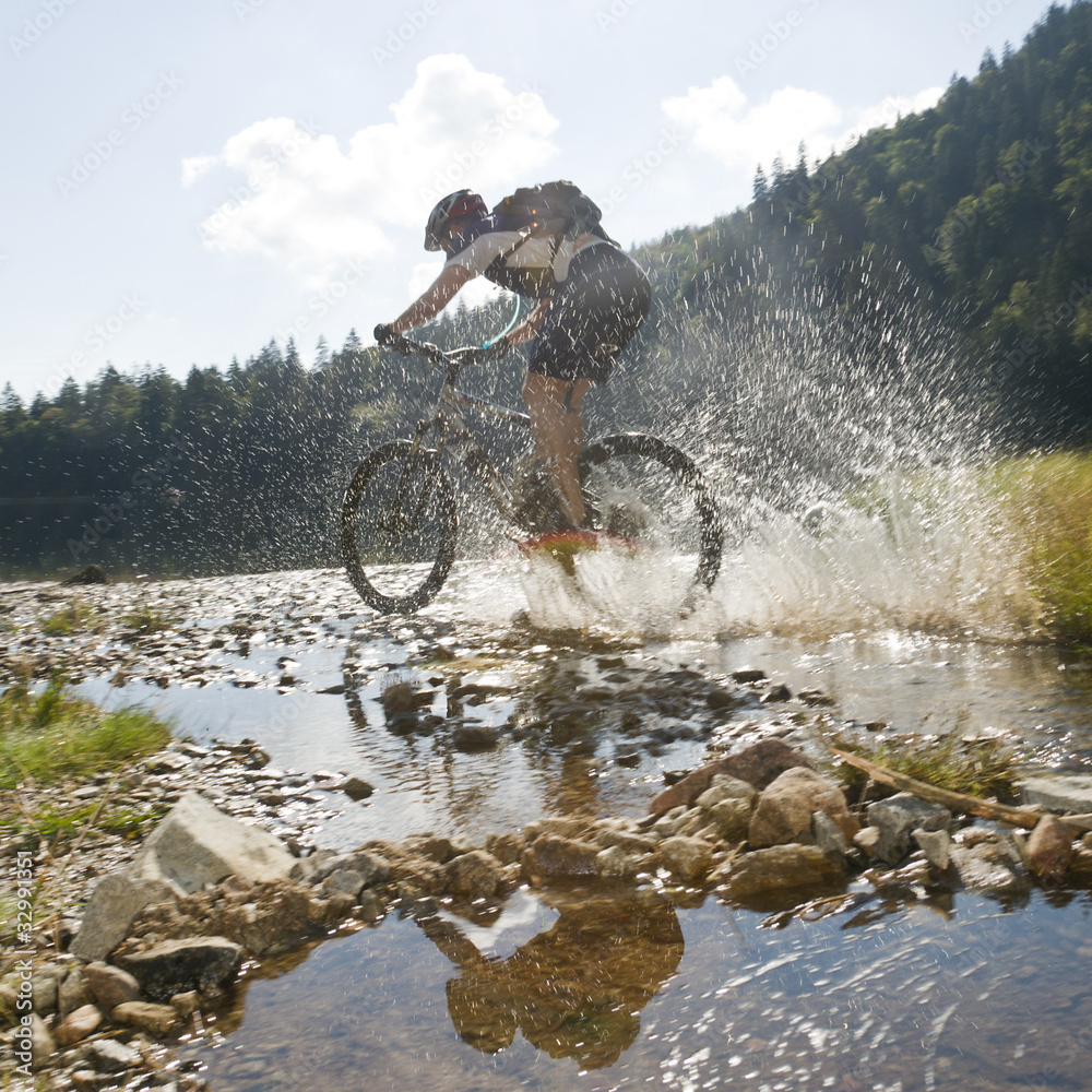 Fototapeta premium Mountainbiker fährt durchs Wasser