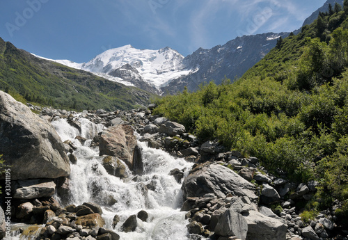 View of high mountains with snow and rapid stream.