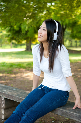 Tableau sur toile beautiful asian woman listening music in the park