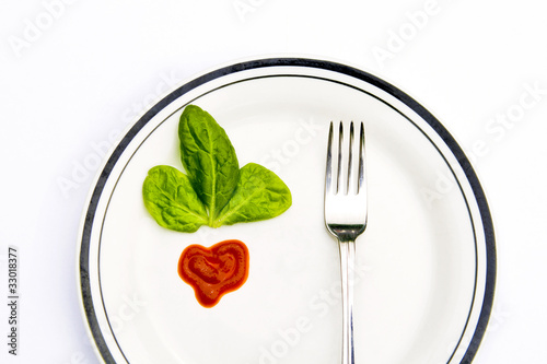 Spinach leaves with heart-shape tomato sauce on a plate