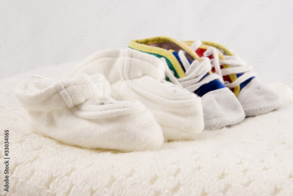 Two Pairs of Tiny Baby Shoes on a White Blanket Two Pairs of Tiny Baby Shoes on a White Blanket