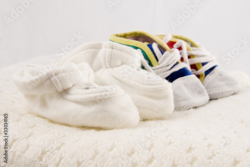 Two Pairs of Tiny Baby Shoes on a White Blanket