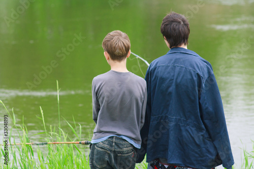 Mother and son catch the fish on the river shore