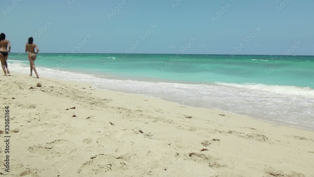 twin sisters in swimsuit running on tropical beach twin sisters in swimsuit running on tropical beach