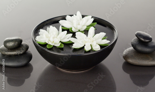 Close up of flowers floating surrounded by stacks of black pebbl