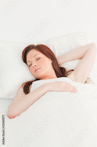 Close-up of a good looking red-haired female sleeping in her bed