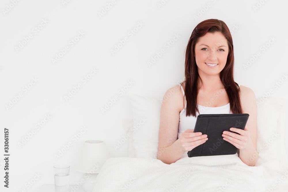 Good looking red-haired woman relaxing with her tablet while sit Good looking red-haired woman relaxing with her tablet while sit