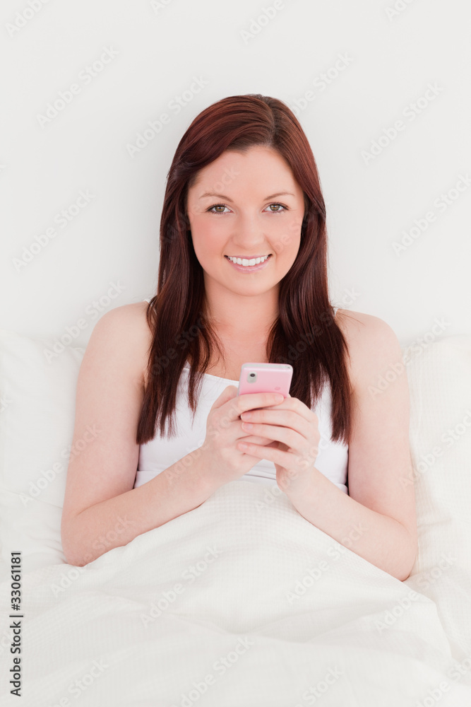 Good looking red-haired woman writing a text on her mobile while Good looking red-haired woman writing a text on her mobile while