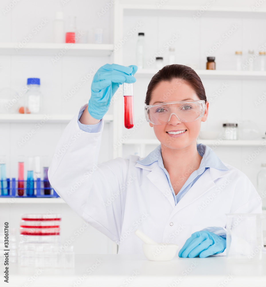 Portrait of a young scientist showing a test tube looking at the Portrait of a young scientist showing a test tube looking at the