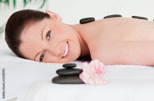 Young woman receiving a black stone massage and a pink carnation