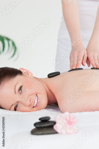 Young redhead woman having a hot stone massage