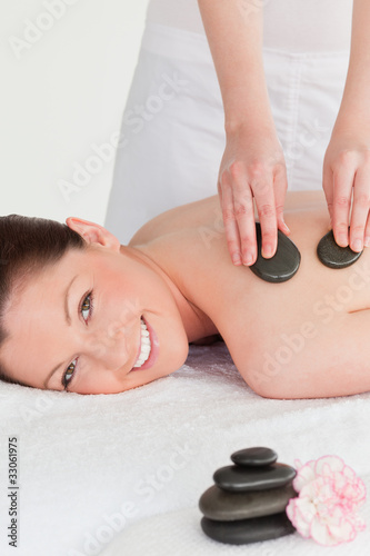 Smiling young redhead woman having a hot stone massage