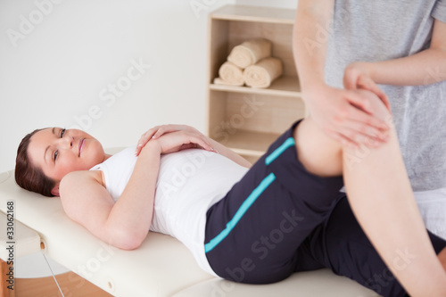 Masseuse massing the knee of a beautiful woman looking a the cam