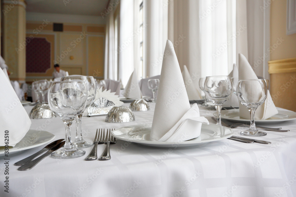 Place settings on an elegant, white dining table in a restaurant Stock