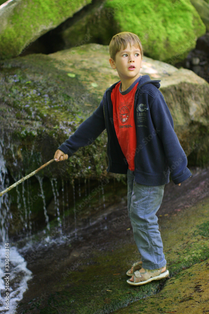 Petit garçon pêchant dans un ruisseau