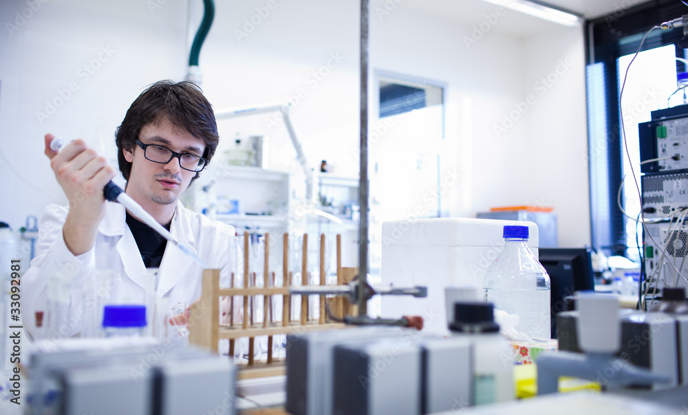 young male researcher carrying out scientific research in a lab young male researcher carrying out scientific research in a lab