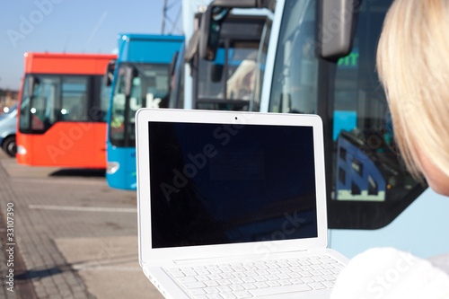 junge blonde frau mit laptop vor bussen