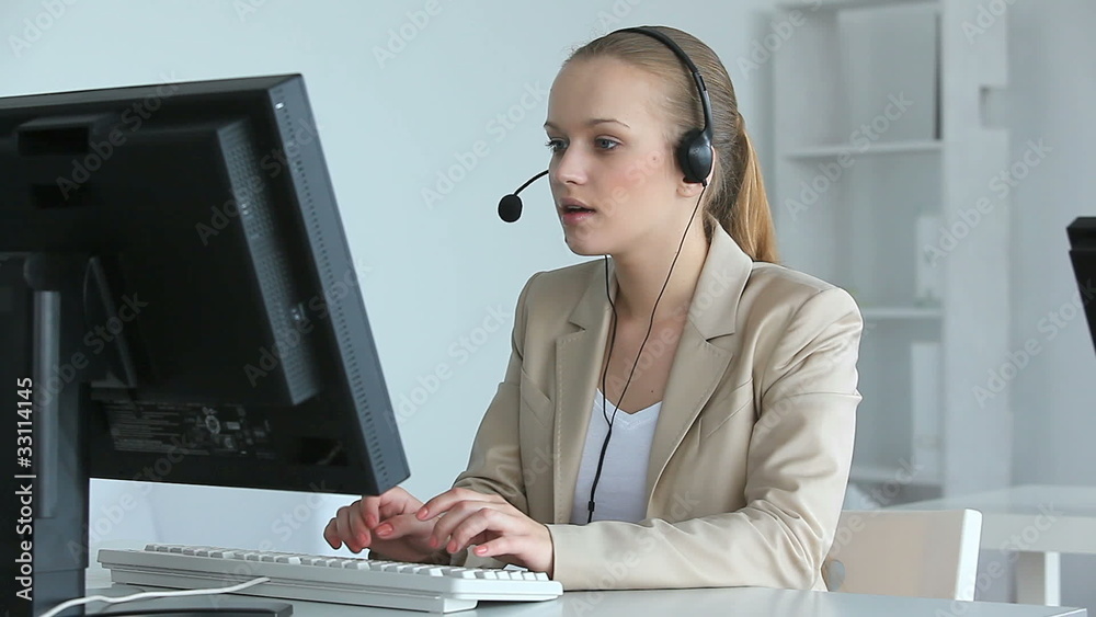 Pretty operator working on computer and answering a call