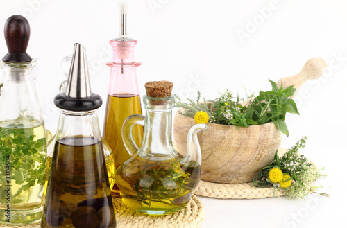 Mortar and pestle with herbs and bottles of olive oil