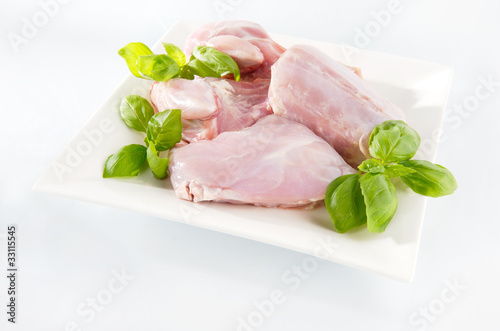 Raw rabbit meat on a plate. Arrangement with mint leaves. photo