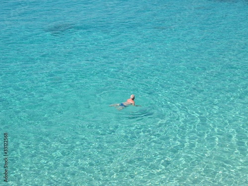 Older man swimming in crystal clear water.