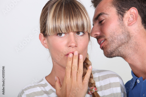 Man telling a secret to a woman