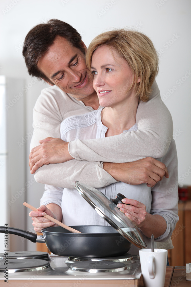 Man hugging a woman cooking at an electric stove Man hugging a woman cooking at an electric stove