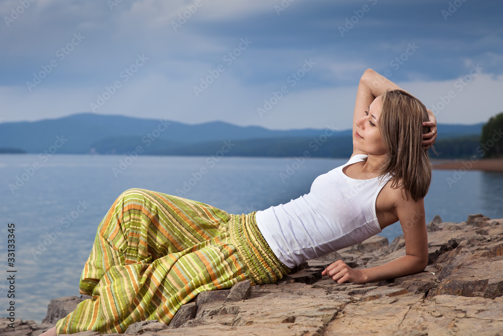 Beautiful happy woman sitting on rock over sea at summer storm d